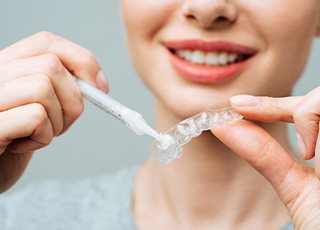 Woman applying whitening gel to applicator