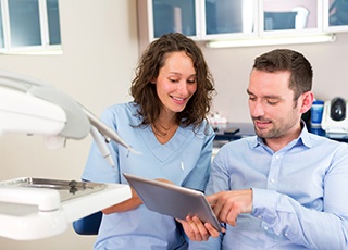 A dentist goes over the process of receiving dental implants with a male patient