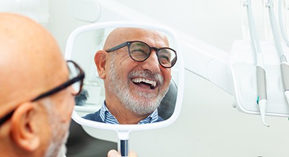 Man with black glasses smiling in reflection in mirror