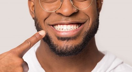 man pointing to his smile after getting cosmetic dentistry questions answered