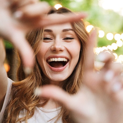 young woman smiling after getting dental bridges in Kernersville