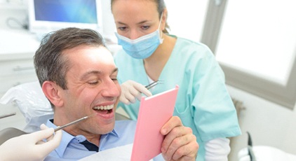 patient looking at dental bridge in Kernersville