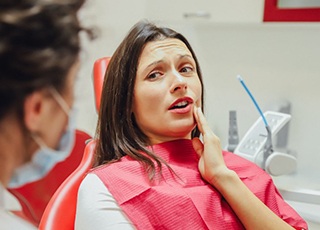 Patient rubbing her jaw as she explains dental emergency to dentist