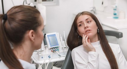 A young woman visiting her dentist for dental implant salvage