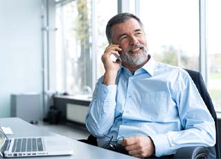 businessman sitting at his desk and talking on his cell phone