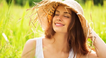 Woman smiling in a field of grass after sedation dentistry visit