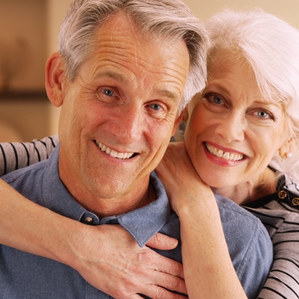 Older man and woman smiling after oral cancer screenings