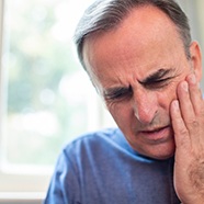 Man in need of emergency dentistry holding jaw in pain