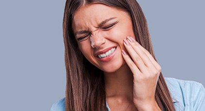 Woman holding cheek before T M J and bruxism therapy