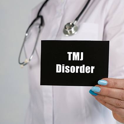 Doctor holding sign that says, “TMJ Disorder”
