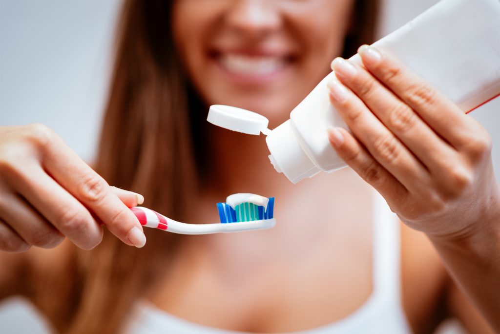 close-up of a woman putting paste on toothbrush