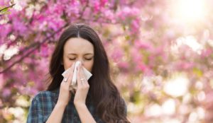 woman blowing nose with spring allergies