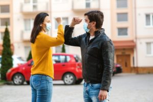 two masked people greeting with an elbow bump 