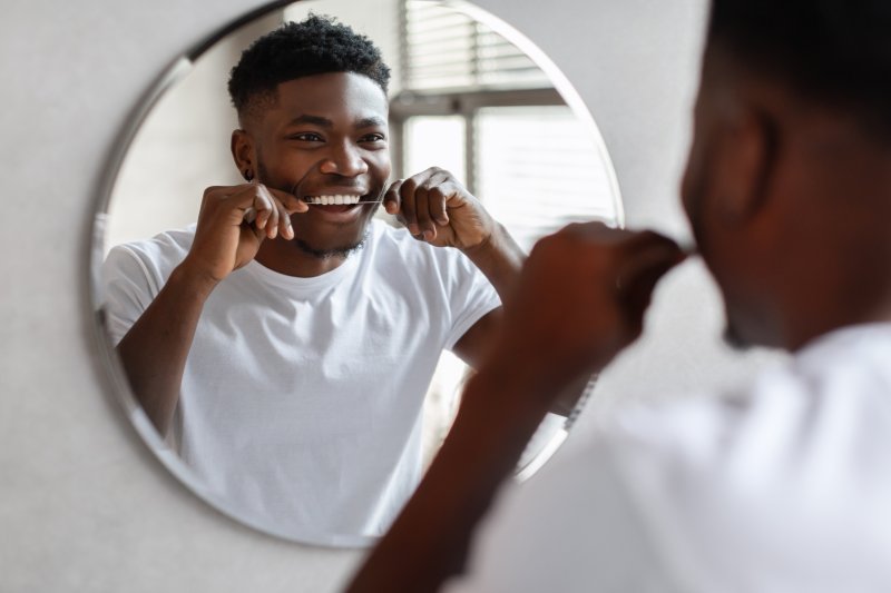 A man flossing in the bathroom 