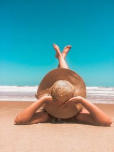 Woman wearing large hat relaxing on beach